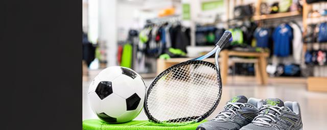 Sporters met voetbal, tennisracket en hardloopschoenen in een lichte sportwinkel